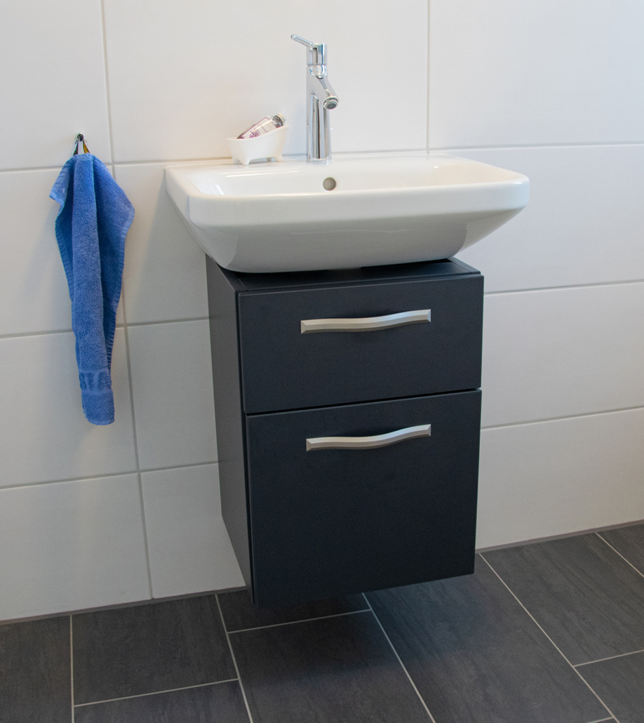 Waschbecken-Unterschrank in eleganter anthrazitfarbener Matt-Optik mit Edelstahl-Griffleisten.